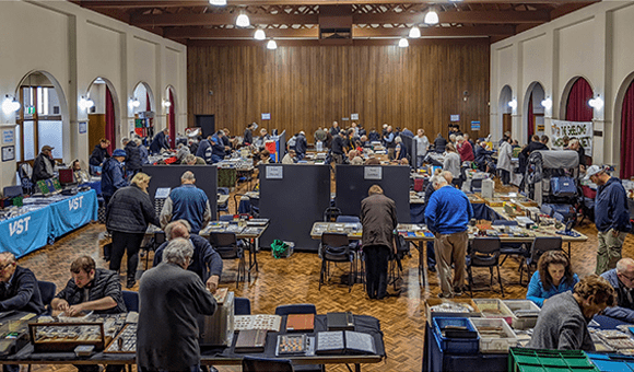 Photo of bustling indoor market with tables of wares set up and shoppers admiring the displays.